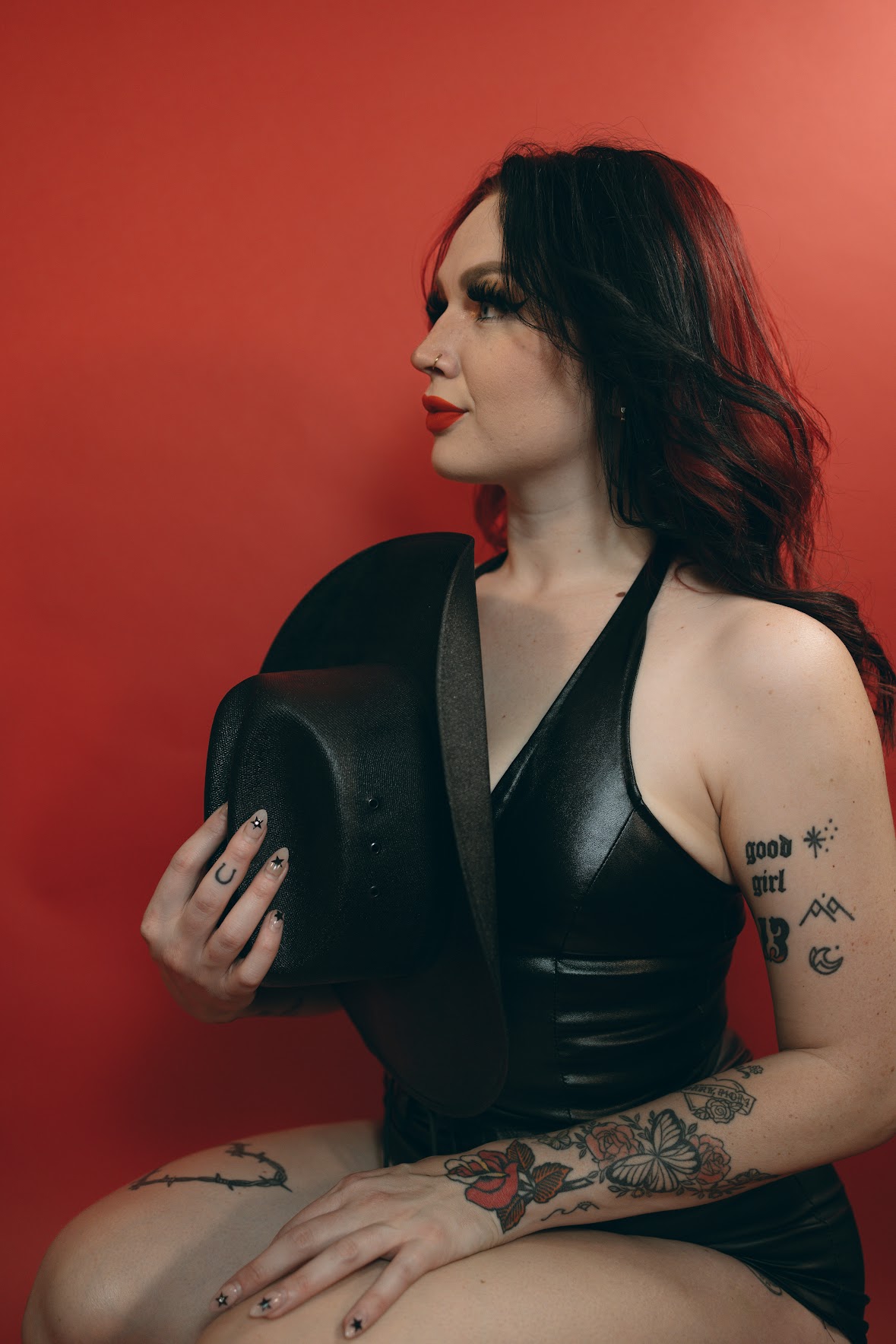 Studio portrait with a black hat on red